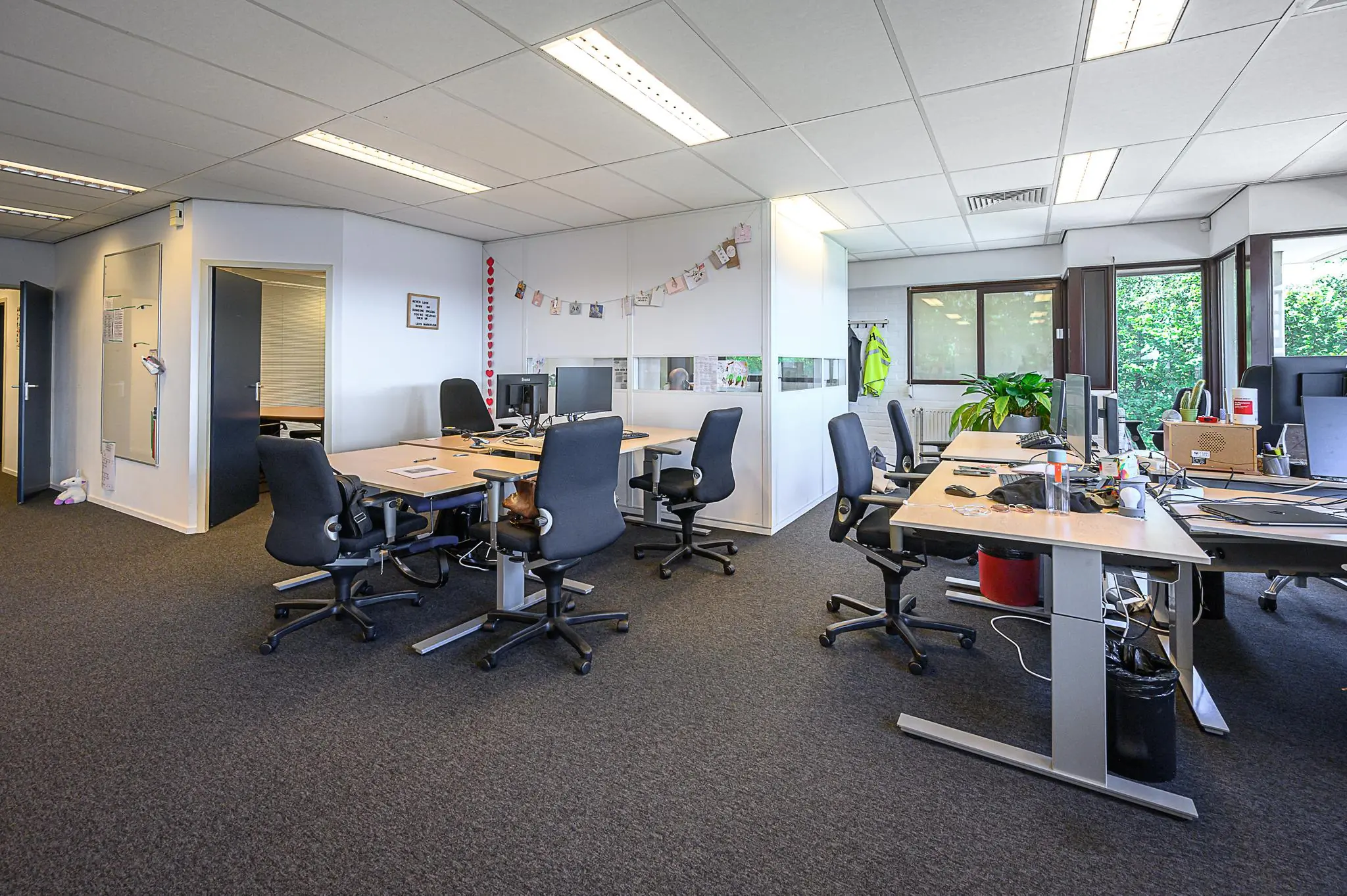 Modern kantoorinterieur met meerdere bureaus, bureaustoelen en computers in een open werkruimte bij De Linie.